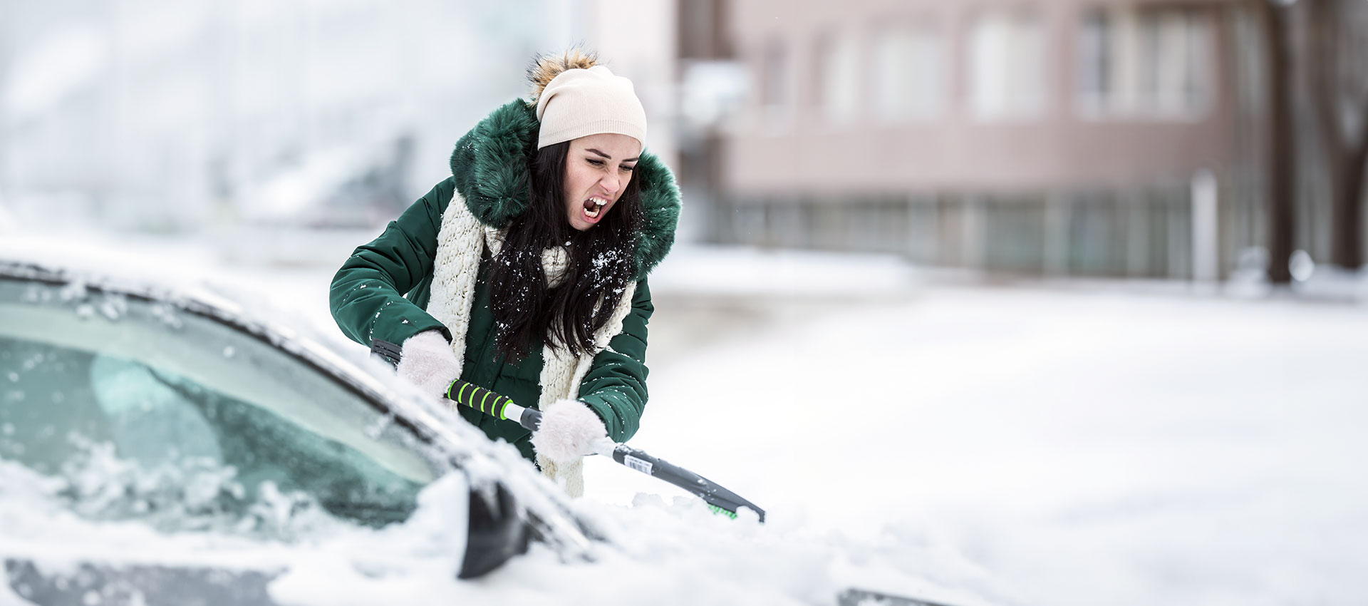 Femme qui déneige son auto qui est fâchée de ne pas avoir d'abri d'auto